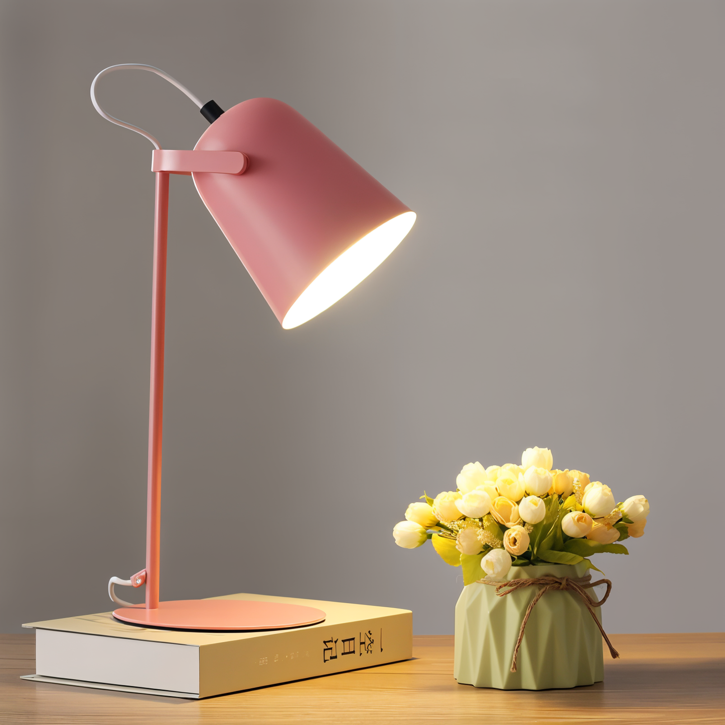 Elegancka lampa stołowa LED w różowym kolorze z subtelnym światłem obok wazonu z kwiatuszkami.